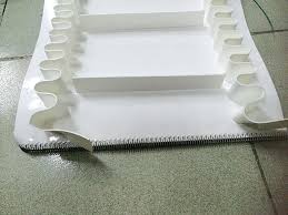 A white food grade PVC belt with moulded cleats standing across its width. A white food grade PVC belt with moulded cleats standing across its width.