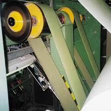 A nylon transmission belt running over the yellow pulleys of a machine on a factory floor. A nylon transmission belt running over the yellow pulleys of a machine on a factory floor.
