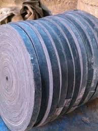 Rolls of balata flat belting stacked on their sides in the works.