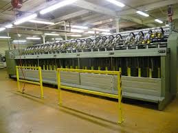 A row of spinning machines, each spindle driven by its own narrow tape.