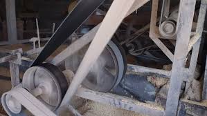 A long flat belt running between two pulleys in a rice mill.