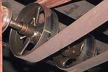 A flat belt running from a line shaft pulley down to the machine below it.
