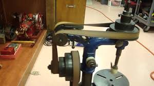 A flat belt driving a bench drilling machine in a workshop.