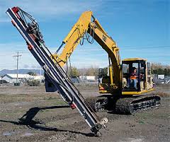 A tracked drilling rig at work on a site, its mast lowered and hoses running along it. A tracked drilling rig at work on a site, its mast lowered and hoses running along it.