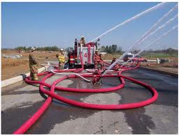 A red delivery hose feeding a pump on a site, water spraying from the discharge. A red delivery hose feeding a pump on a site, water spraying from the discharge.