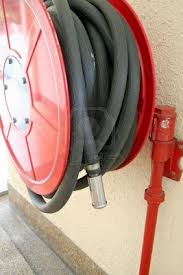 A fire hose reel mounted on a wall with the hose coiled on it and the nozzle stowed. A fire hose reel mounted on a wall with the hose coiled on it and the nozzle stowed.