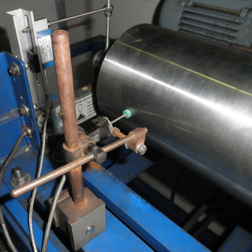 The apparatus that checks a roller for total indicated runout and running noise, the roller mounted between its drive and its instruments. The apparatus that checks a roller for total indicated runout and running noise, the roller mounted between its drive and its instruments.