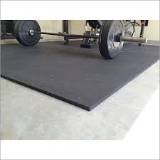 A thick rubber gym mat laid on a floor, with a loaded barbell resting on it.