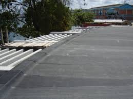 An EPDM membrane laid across a flat roof, with rolls of it still to be unrolled along the edge.