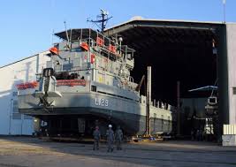 A naval vessel alongside at a shipyard, with the yard sheds behind it. A naval vessel alongside at a shipyard, with the yard sheds behind it.