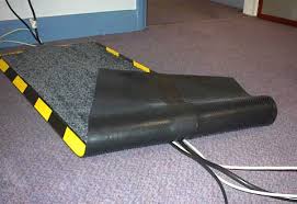 A dielectric carpet laid over cables on an office floor, its edge ramped and striped yellow and black. A dielectric carpet laid over cables on an office floor, its edge ramped and striped yellow and black.
