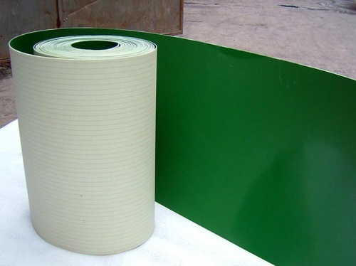 A roll of PVC belting, green on its top face and pale on the fabric underside.