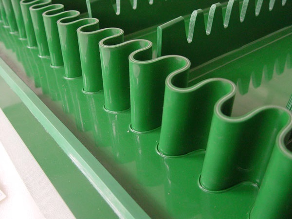 A green belt with corrugated sidewalls and cleats between them, for carrying loose material up an incline.