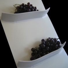Two curved flights on a white belt, each holding a pile of dark berries.