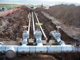 Three large gate valves fitted into a pipeline laid in an open trench.