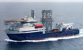 A supply vessel under way past an offshore platform.