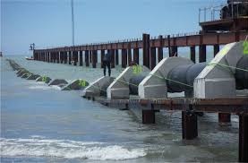 A line of water intake screens along a jetty, with the structure running out into the sea.