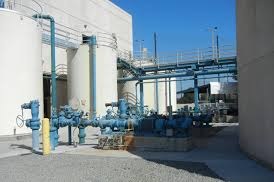 Blue valves and pipework outside a process plant building.